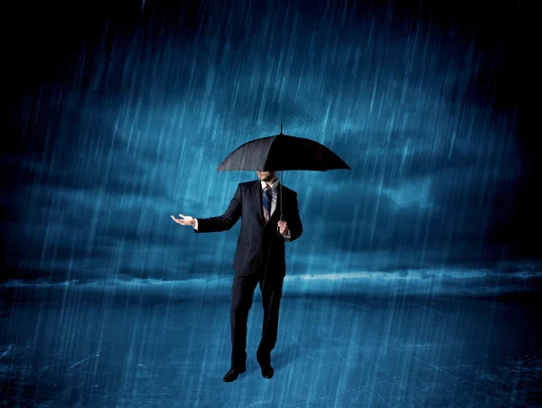 Business man standing in rain with an umbrella — Stock Photo, Image