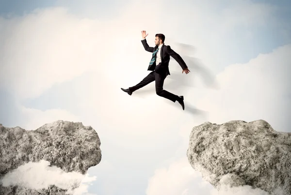 Happy business man jumping over a cliff — Stock Photo, Image