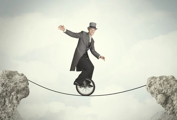Hombre de negocios valiente montando un monociclo entre acantilados — Foto de Stock