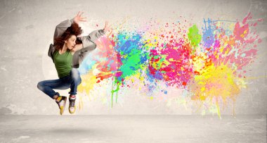 Happy teenager jumping with colorful ink splatter on urban backg clipart