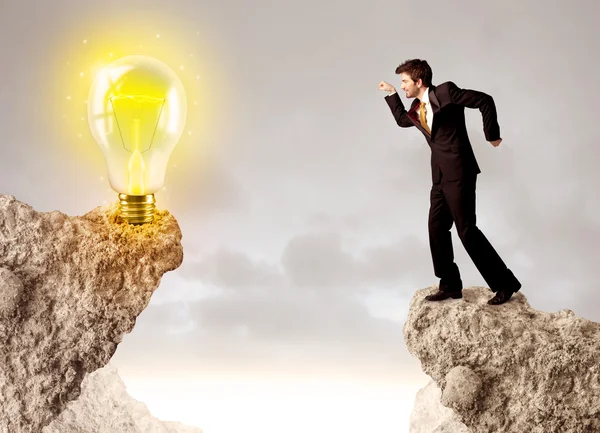 Businessman on rock mountain with idea bulb — Stock Photo, Image