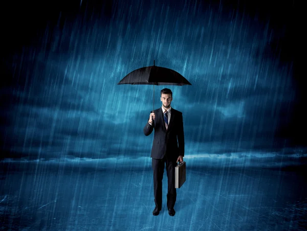 Hombre de negocios de pie bajo la lluvia con un paraguas — Foto de Stock