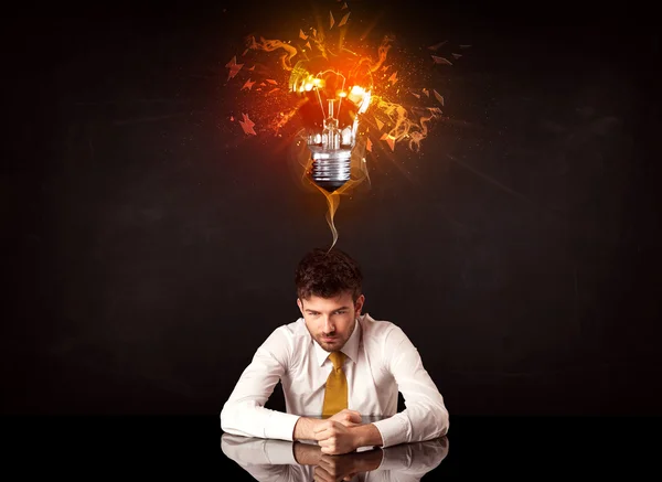 Uomo d'affari seduto sotto una lampadina soffiante idea — Foto Stock