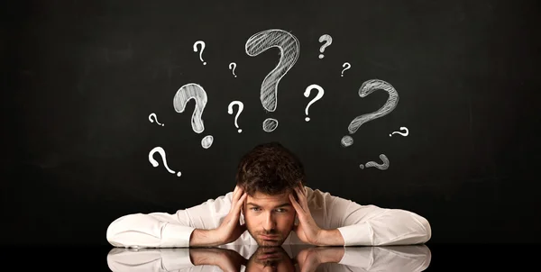 Sitting businessman under question marks — Stock Photo, Image