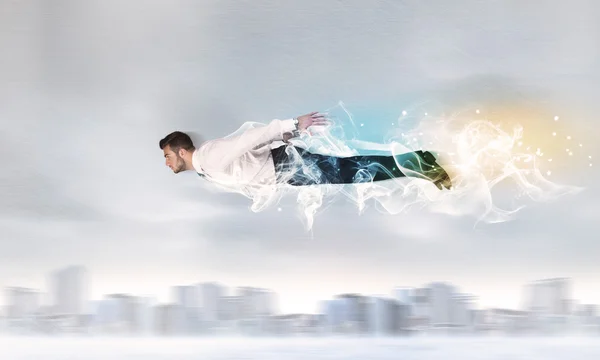 Hero superman flying above city with smoke left behind — Stock Photo, Image