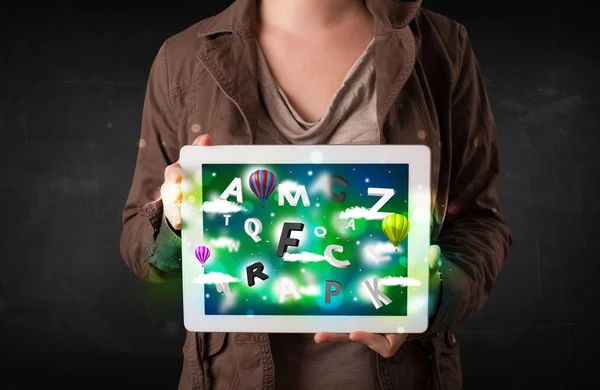 Joven mostrando tableta con letras abstractas y cielo —  Fotos de Stock