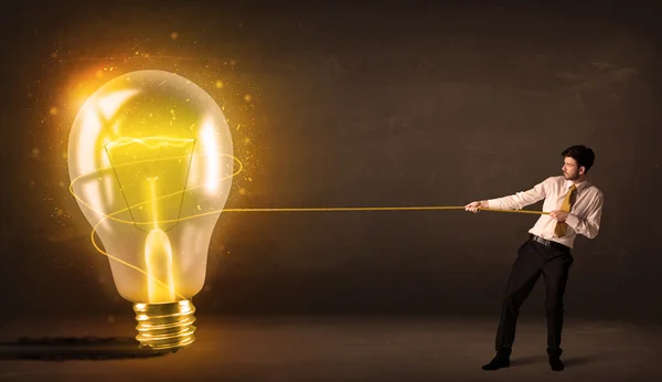 大きな明るい白熱電球を引っ張るビジネス男性 — ストック写真
