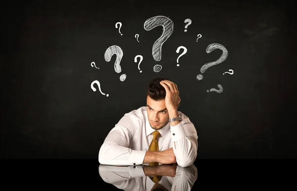 Sitting businessman under question marks — Stock Photo, Image