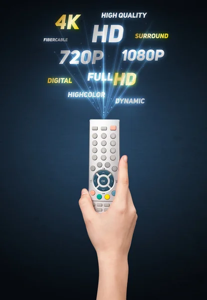 Hand with remote control and multimedia properties — Stock Photo, Image