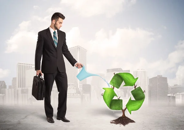 Geschäftsmann wässert grünen Recycling-Schilderbaum vor Stadthintergrund — Stockfoto