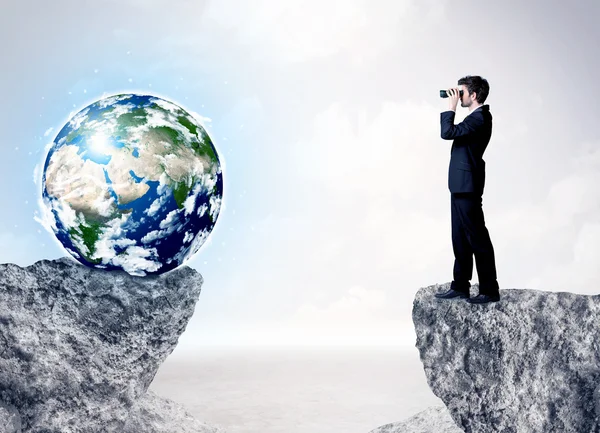 Zakenman op rock berg met een globe — Stockfoto