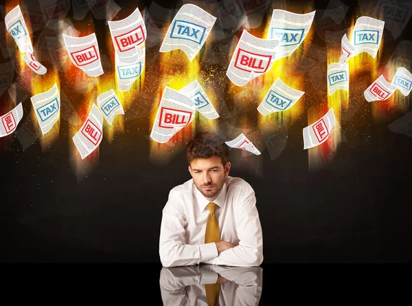 Depressiver Geschäftsmann sitzt unter brennenden Steuer- und Rechnungspapieren — Stockfoto