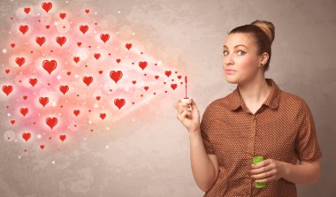 Güzel genç kız kırmızı kalp sembolleri üflüyor.