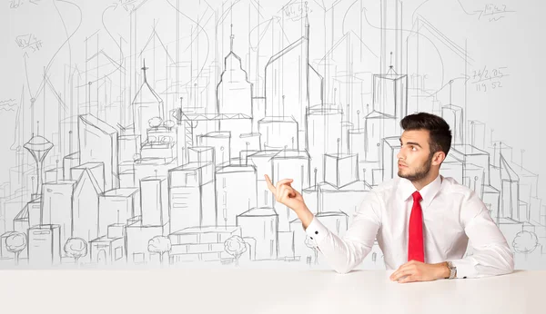 Businessman sitting at the white table with hand drawn buildings — Stock Photo, Image