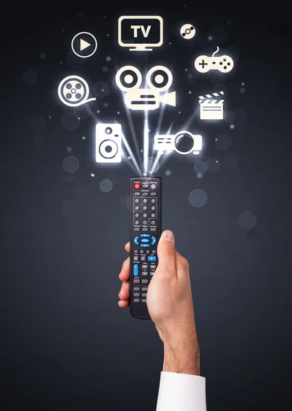 Hand with remote control and media icons — Stock Photo, Image