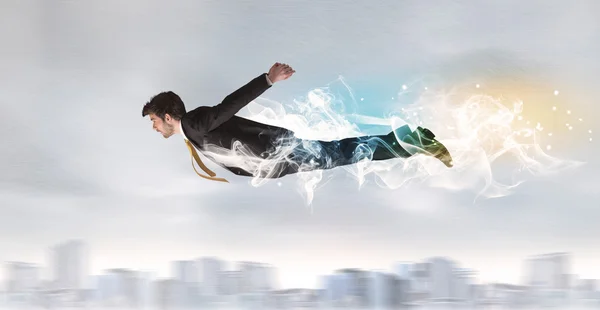 Hero superman flying above city with smoke left behind — Stock Photo, Image