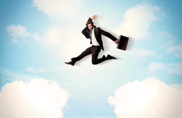 Business person jumping over clouds in the sky — Stock Photo, Image