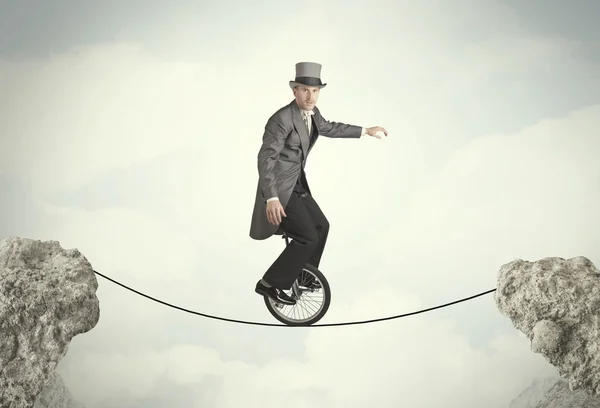 Brave business man riding an mono cycle between cliffs — Stock Photo, Image