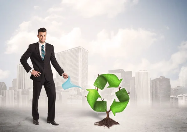 Business man watering green recycle sign tree on city background — Stock Photo, Image