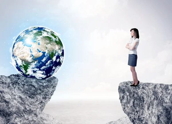 Businesswoman on rock mountain with a globe — Stock Photo, Image