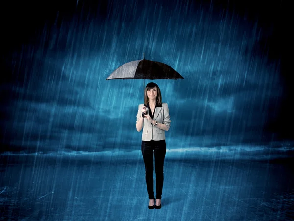 Business woman standing in rain with an umbrella — Stock Photo, Image