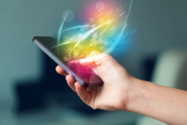 Ручной смартфон с абстрактными светящимися линиями — стоковое фото