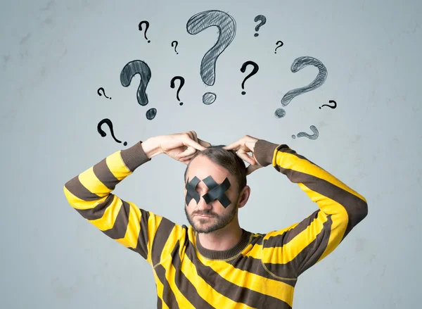 Young man with glued eye and question mark symbols — Stock Photo, Image