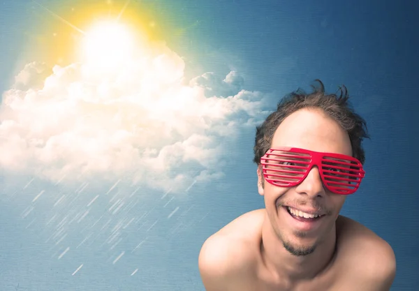 Güneş gözlükleriyle bulutlara ve güneşe bakan genç adam — Stok fotoğraf
