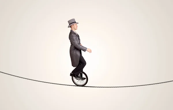 Экстремальный бизнесмен катается на моноцикле по веревке — стоковое фото