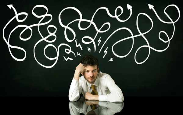 Depresivní podnikatel sedící pod kreslenými směrovými čárami — Stock fotografie