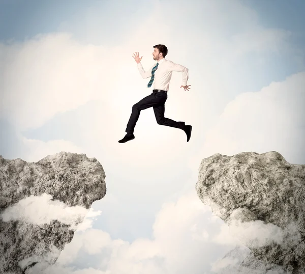 Happy business man jumping over a cliff — Stock Photo, Image