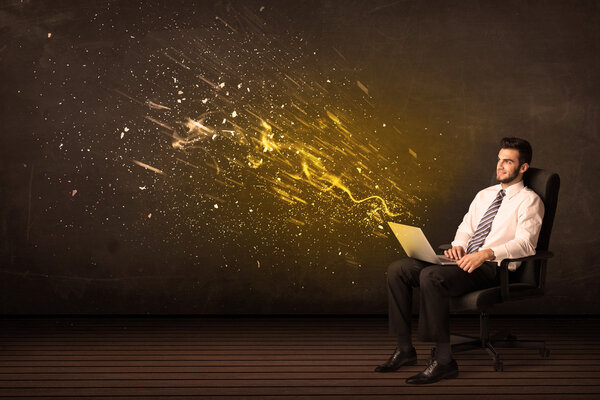 Businessman with laptop and energy explosion on background