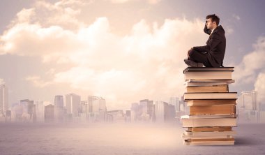 Şehrin üstündeki kitap yığınında oturan adam.