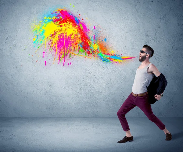 Hipster guy shouting colorful paint on wall — Stock Photo, Image