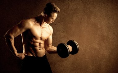 Kas formundaki vücut geliştirici sporcu ağırlık kaldırıyor 