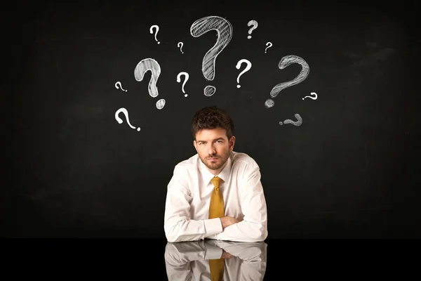 Sitting businessman under question marks — Stock Photo, Image