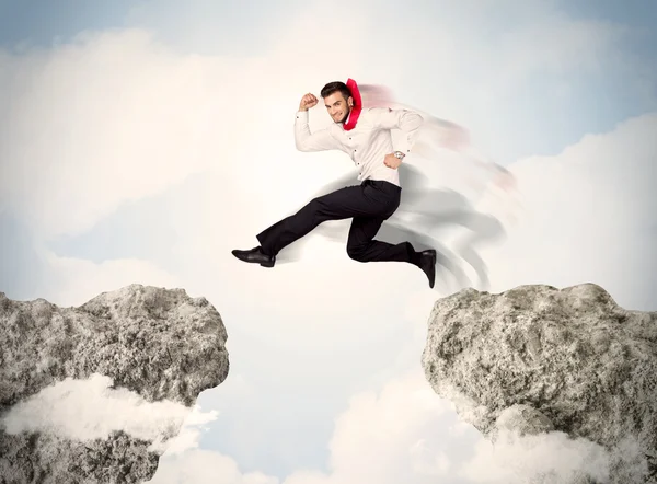 Happy business man jumping over a cliff — Stock Photo, Image