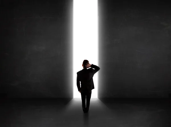 Persona de negocios mirando a la pared con apertura de túnel de luz — Foto de Stock