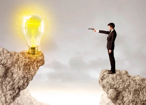 Businessman on rock mountain with idea bulb — Stock Photo, Image