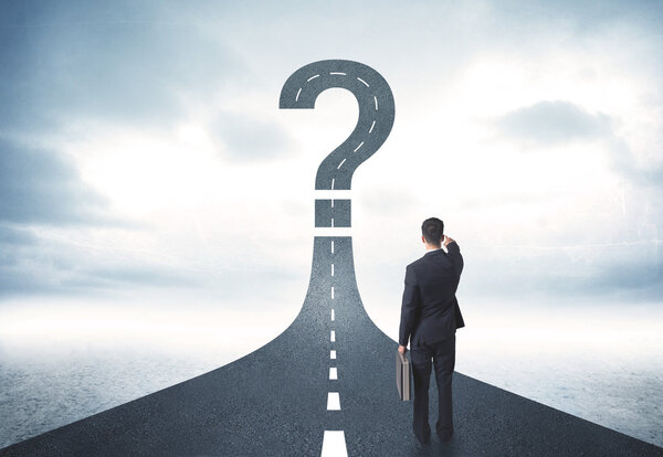 Деловой человек шатается по дороге с вопросительным знаком