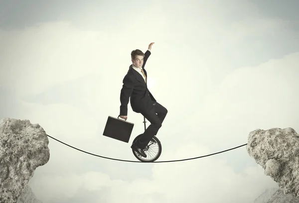 Brave business man riding an mono cycle between cliffs — Stock Photo, Image