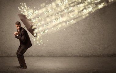 İş adamı dolar yağmuruna karşı şemsiye tutuyor