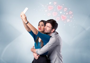 Aşık çift kırmızı kalple selfie çekiyor.