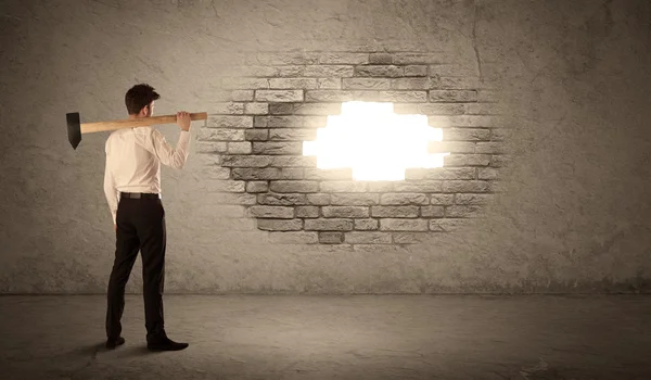 Business man hitting brick wall with hammer and opening a hole — Stock Photo, Image