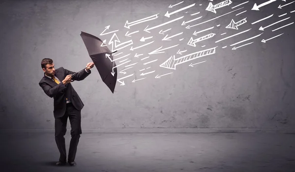 Homem de negócios de pé com guarda-chuva e flechas desenhadas batendo nele — Fotografia de Stock