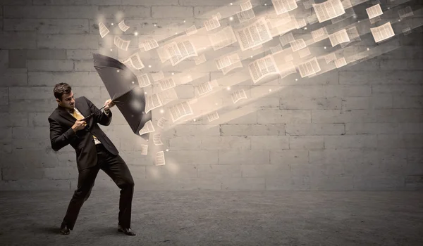 Business man protecting with umbrella against wind of papers — Stock Photo, Image