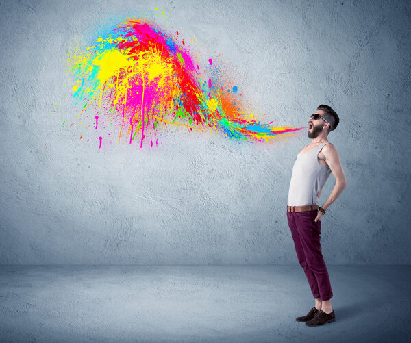 Hipster guy shouting colorful paint on wall