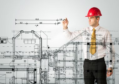 Genç bir mimar ev planı çiziyor.