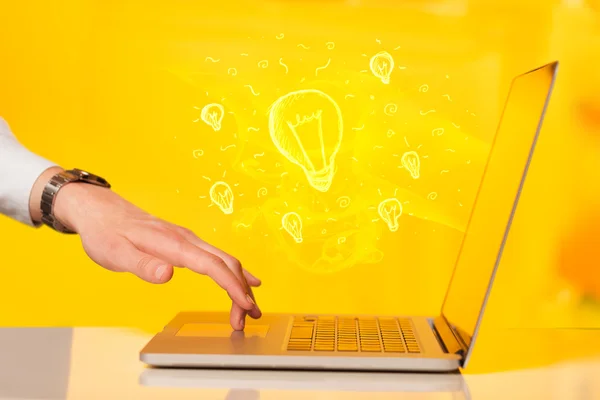 Primo piano di mano con laptop e lampadina idea — Foto Stock