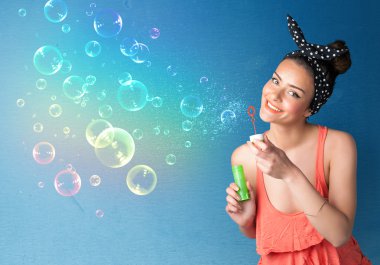 Mavi arka planda renkli kabarcıklar çıkaran güzel bayan.